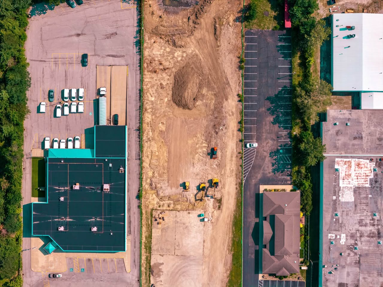 Aerial drone view of the cleared and graded Apex Strength Club site on Liberty Avenue with excavators installing utilities